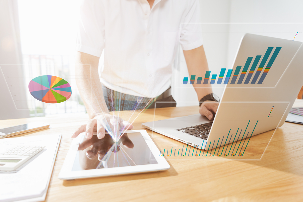 Businessman,Using,Laptop,And,Digital,Tablet,To,Analyse,Sales,Report
